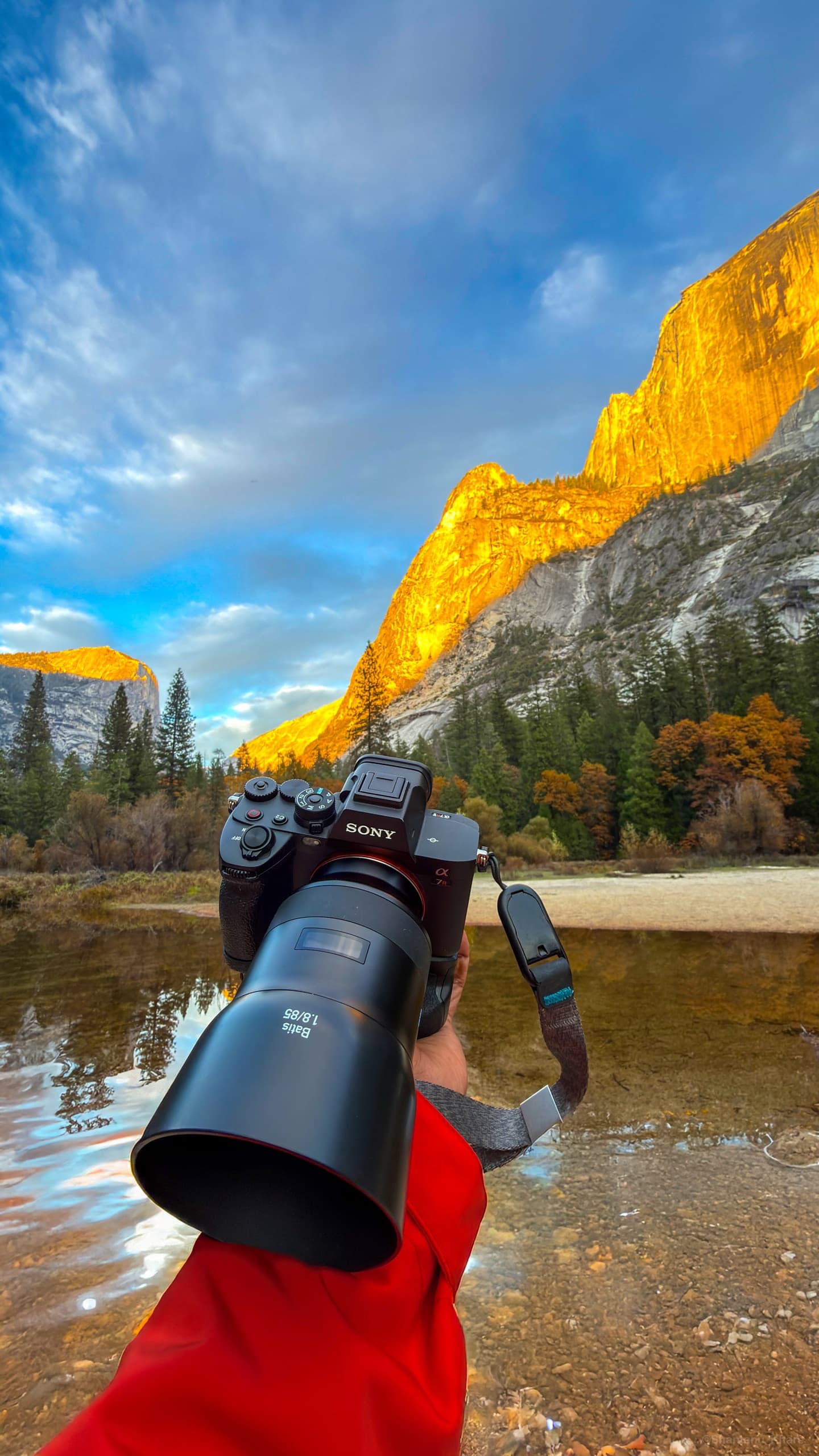 Behind the scenes — a Sony camera framing golden-hour cliffs mirrored in a still lake, Yosemite.