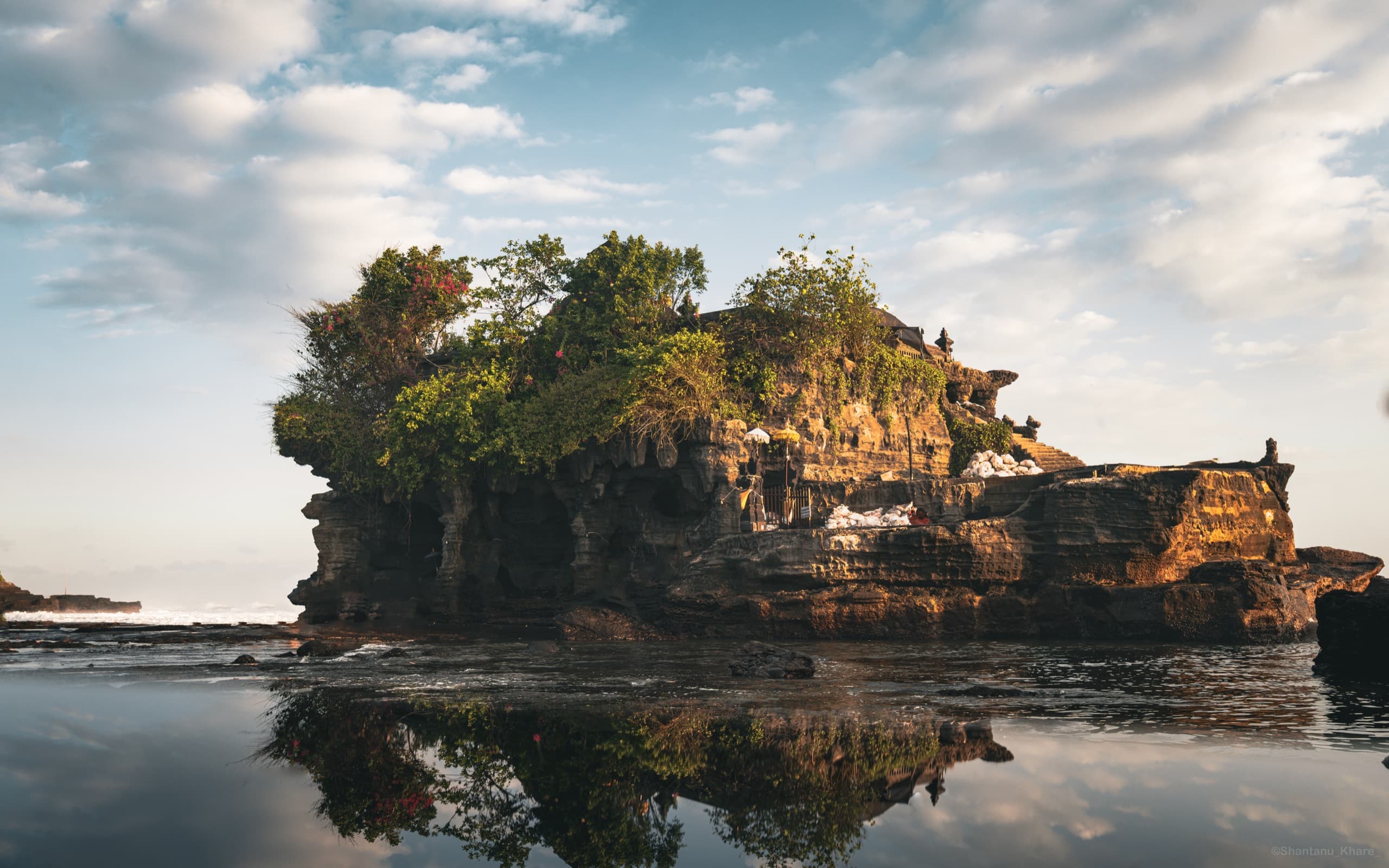 Travel photography — Tanah Lot sea temple mirrored in the wet shore at dusk, Bali.